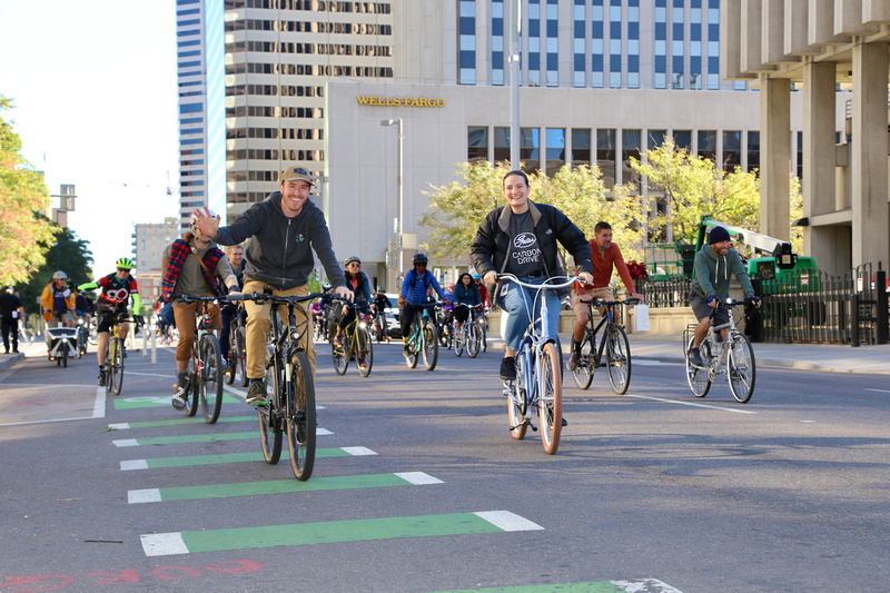 Two riders in focus while other bikers ride behind them down the streets of Denver