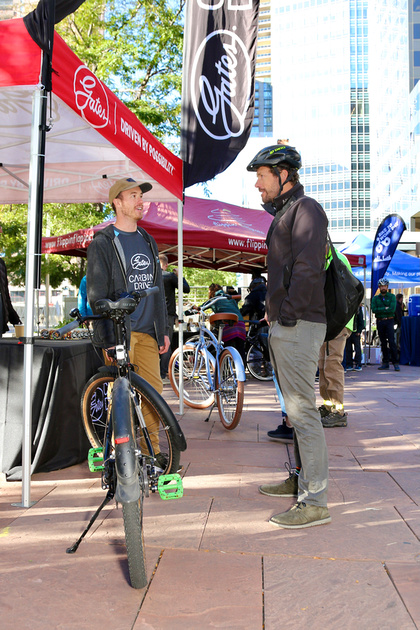 Two men discuss a belt drive bicycle