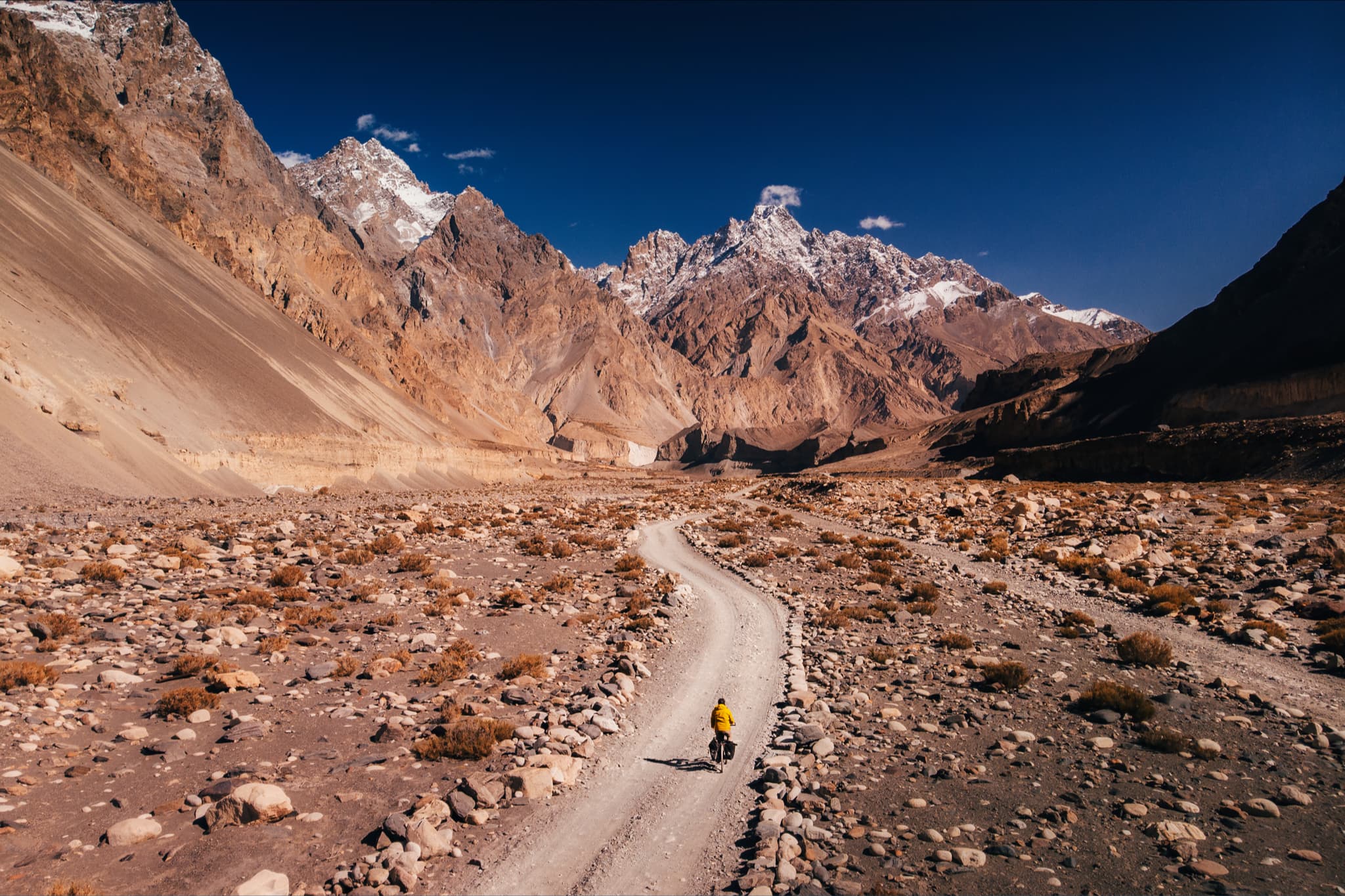 Kamran Ali riding a belt driven bike on a path between a couple of lonely mountains